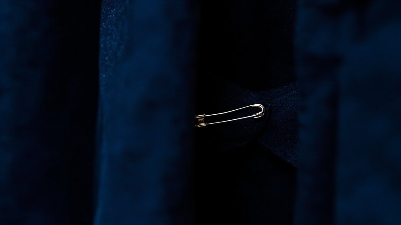 Inside of a dress showing a safety pin temporarily taking in the side seam at the waist for a quick fit adjustment