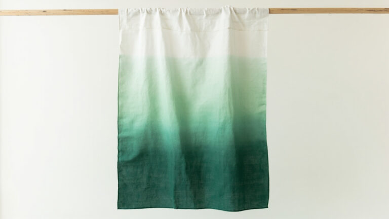 White cotton fabric displaying a smooth vertical ombre gradient from light sage to deep forest green