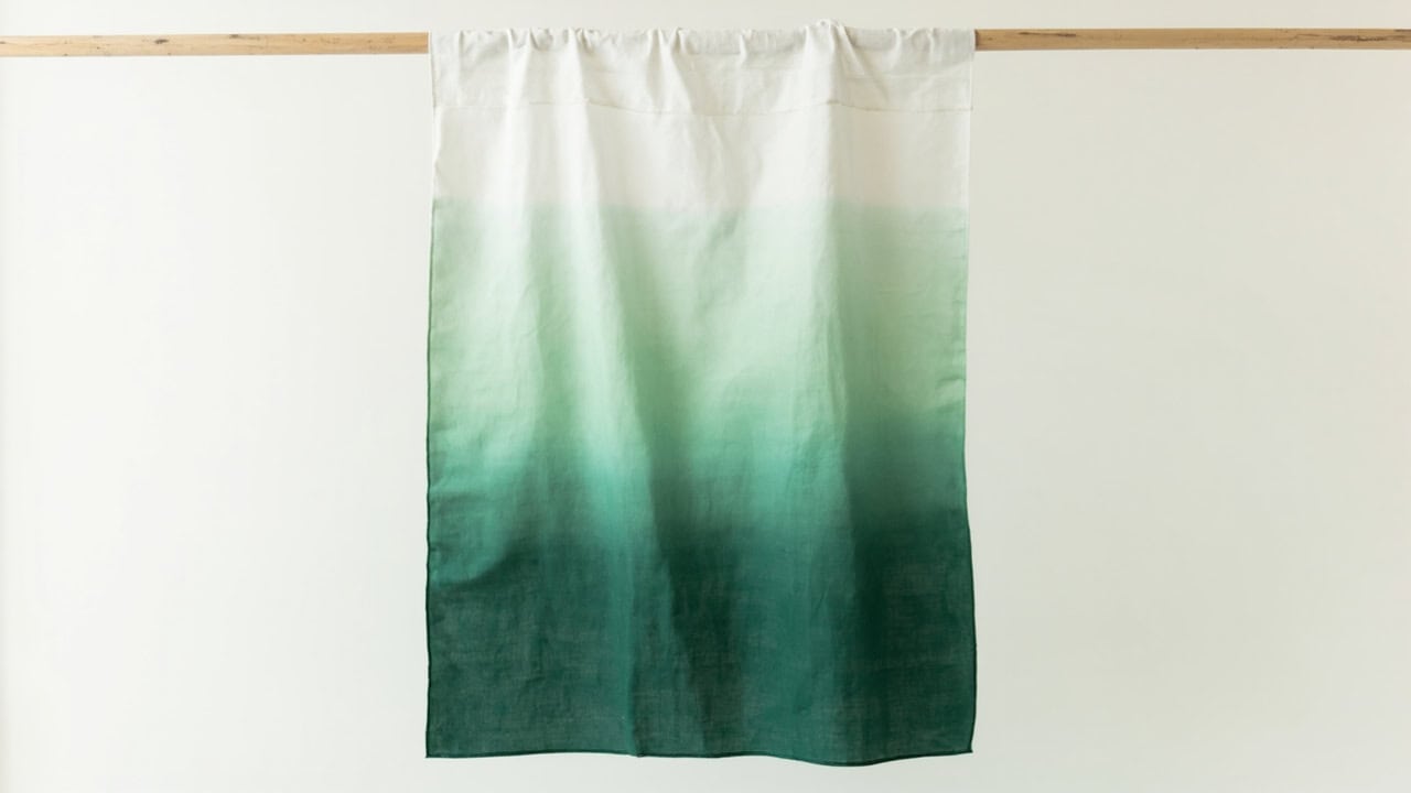 White cotton fabric displaying a smooth vertical ombre gradient from light sage to deep forest green