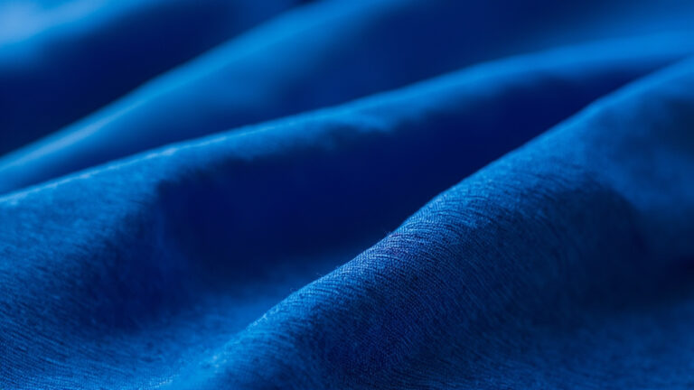 Macro photograph of polyester fabric weave showing uniform synthetic fiber construction with smooth texture