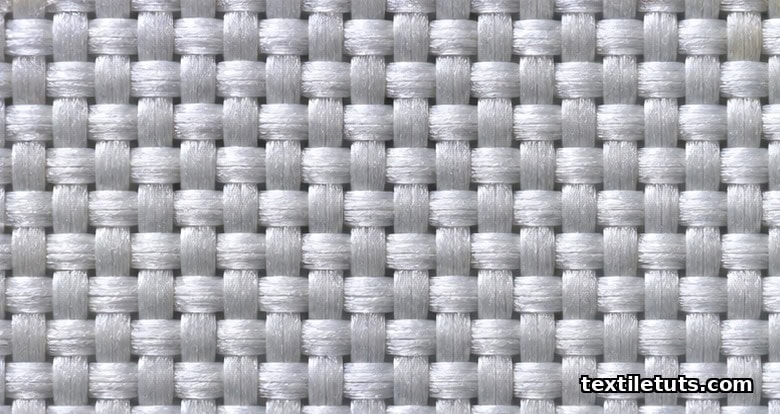 Macro close-up of a tightly woven polyester lining fabric showing perpendicular warp and weft yarn crossings where anti-slip finishes anchor the yarns.