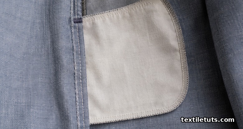 Interior view of a garment side seam with a concealed pocket-bag piece sandwiched between the seam allowances.