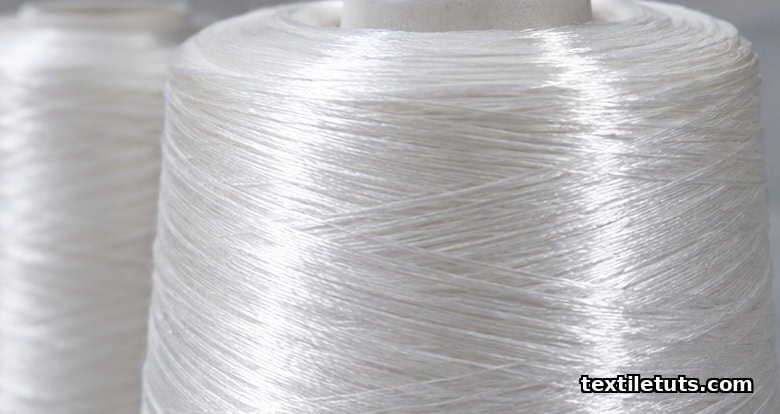 Close-up of smooth lustrous mercerized cotton yarn bundles on a spool catching directional light to show silk-like sheen.