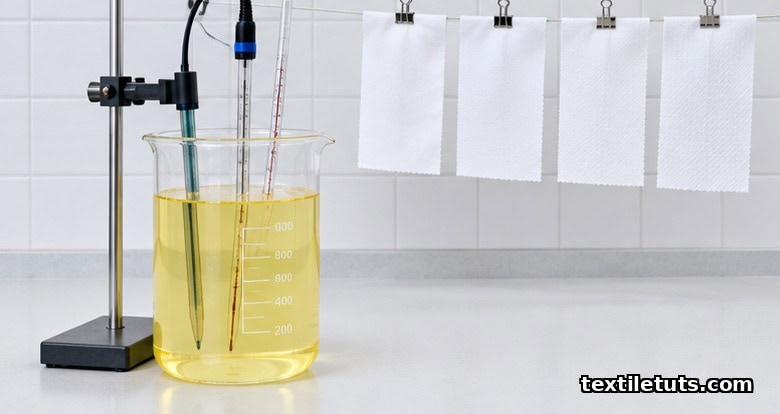 Laboratory beaker of pale-yellow sodium chlorite solution with pH probe and thermometer on a white lab bench.