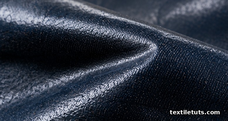 Close-up of deep indigo waxed denim showing the characteristic dry sheen and waxy surface film from a paraffin coating.