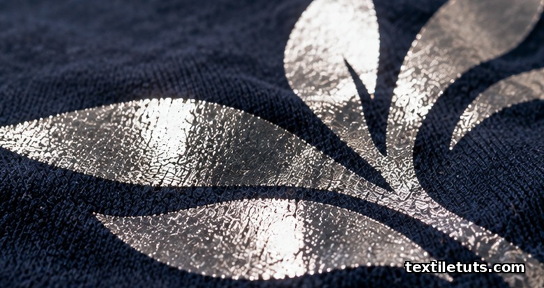 Close-up of metallic silver foil finish bonded onto dark navy cotton fabric showing reflective highlights and bonded metallic layer.