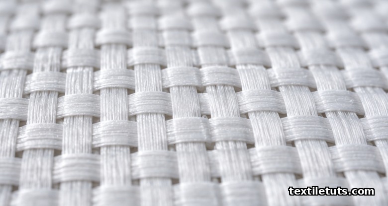 Macro close-up of woven geotextile fabric showing flat warp and weft polypropylene tapes interlacing in plain weave.