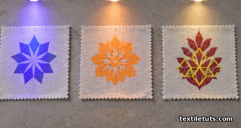 Three cotton swatches under UV light reveal a blue-violet, an orange, and a yellow-over-red photochromic print layered over a permanent undercolor.