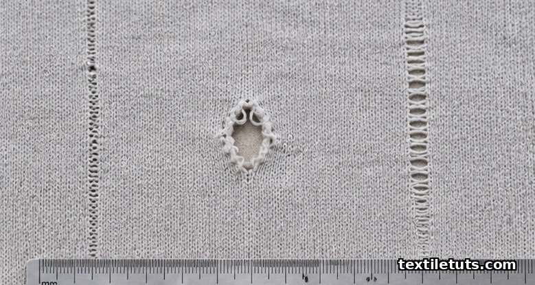 Knit fabric panel on an inspection table showing a needle line, a press-off hole, and a drop stitch defect side by side.