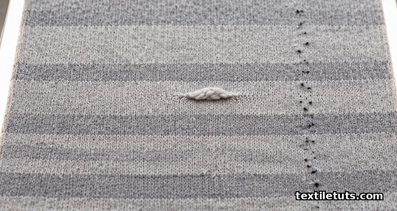 Heather-grey knit fabric on a backlit frame showing horizontal barre bands, a thick slub, and dark fly contamination specks.