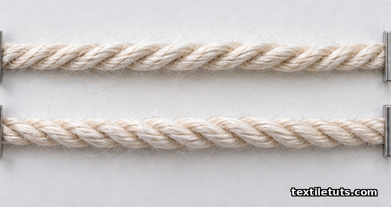 Two yarn specimens pinned side by side on a white card, the upper showing Z-twist spirals and the lower showing S-twist spirals.